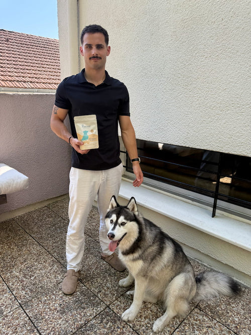 Client tenant un sachet de complément anti-stress Blucove à côté de son husky