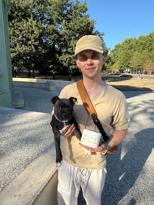 Homme tenant son chien et un pot de complément anti-stress Blucove en extérieur